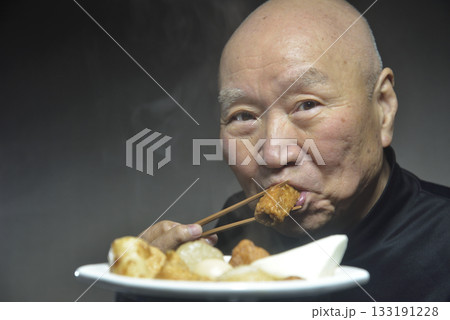 湯気の立ち昇るおでんを食べる笑顔の老人 133191228