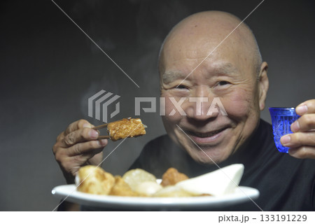 湯気の立ち昇るおでんを食べる笑顔の老人 133191229