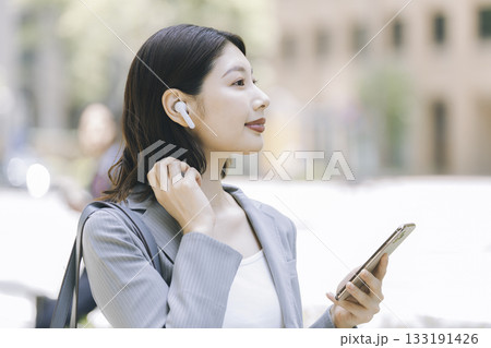 イヤホンをつけスマホを持ったビジネスウーマンの横顔 イヤホンをつけスマホを持ったビジネスウーマンの横顔 133191426