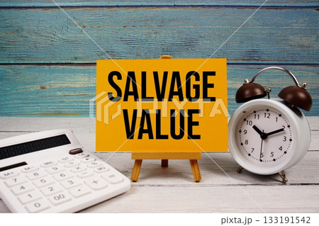 Salvage Value text written on paper card with calculator and alarm clock on wooden background 133191542