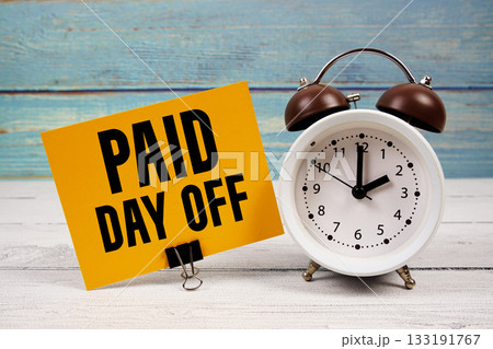 Paid Day Off text written on paper card with alarm clock on wooden background Paid Day Off text written on paper card with alarm clock on wooden background 133191767