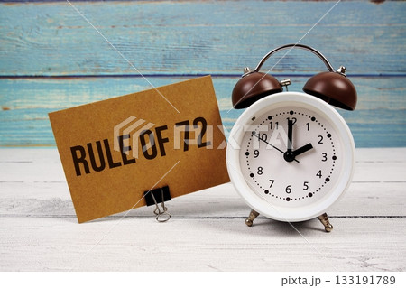 Rule Of 72 text written on paper card with alarm clock on wooden background 133191789