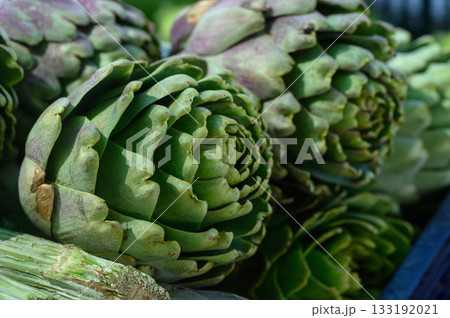Freshly harvested artichokes piled together in a vibrant farmers market stall on a sunny afternoon Freshly harvested artichokes piled together in a vibrant farmers market stall on a sunny afternoon 133192021