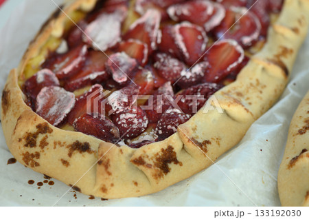Delicious pastries filled with fresh strawberries resting on a baking sheet in a rustic kitchen during the late afternoon light 133192030