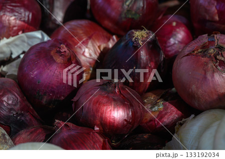 Colorful assortment of fresh red onions displayed at a bustling market during the vibrant afternoon hours in late summer 133192034