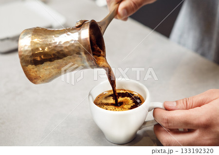 Traditional Turkish Coffee Being Poured From Copper Cezve Into White Cup 133192320