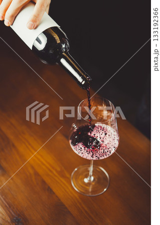 Close up shot of sommelier pouring red wine from bottle in glass 133192366