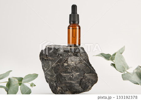 Serum, massage oil in glass dropper bottle on basalt. 133192378