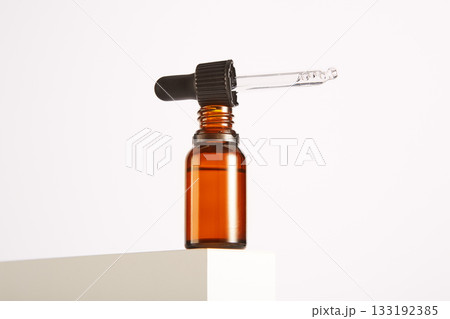 Black cap with pipette lies on open brown glass bottle. Black cap with pipette lies on open brown glass bottle. 133192385