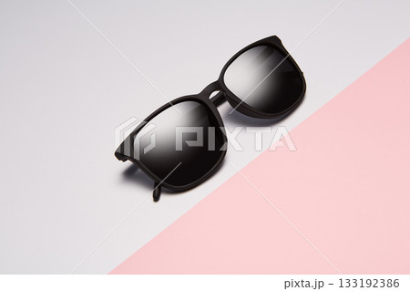 Sun glasses, folded shades lie diagonally on pink. 133192386