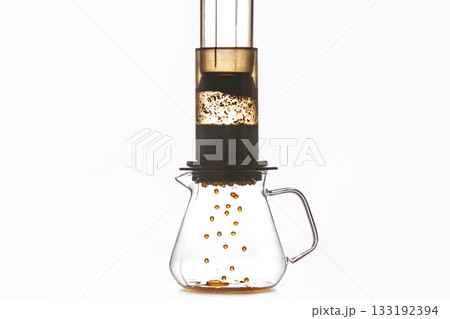 Brewing of Coffee by Creates Pressure Aeropress Method Where Drops Flow From Flask Into Glass Pot, Creating Rich and Fragrant Coffee Drink Against White Background with a Free Copy Space 133192394