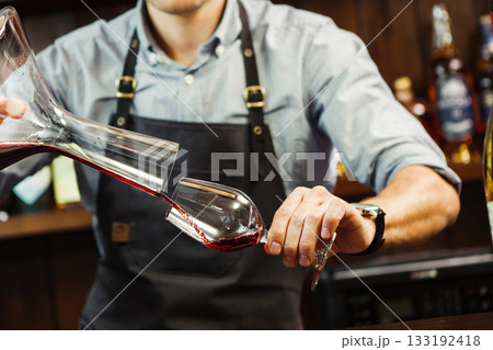 Sommelier pouring wine into glass from mixing bowl. Male waiter Sommelier pouring wine into glass from mixing bowl. Male waiter 133192418