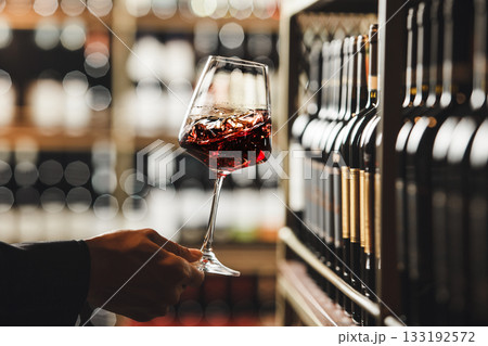 Close-Up View of Person Swirling Red Wine in Cellar Atmosphere Close-Up View of Person Swirling Red Wine in Cellar Atmosphere 133192572