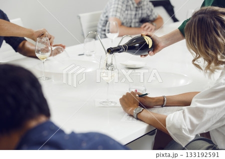 Bartender pours sparkling wine into glasses for the participants of the training held at the sommelier training school. 133192591