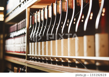 Bottles of still wine on the shelf, close-up image of alcoholic beverages in the wine cellar. Bottles of still wine on the shelf, close-up image of alcoholic beverages in the wine cellar. 133192619