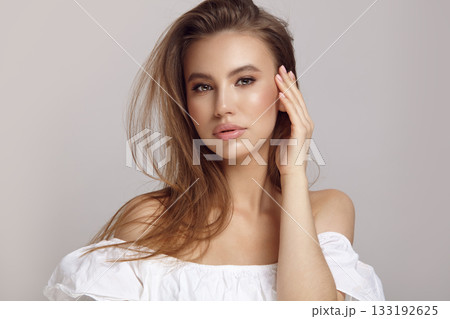 Seductive woman touches cheek looking at camera in studio Seductive woman touches cheek looking at camera in studio 133192625