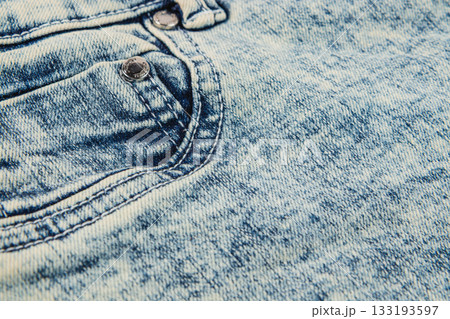 Close-up of faded denim fabric with pockets and stitches in natural light 133193597