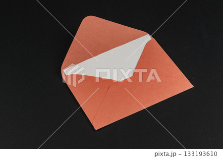 Orange envelope with a white insert lying on a black background 133193610