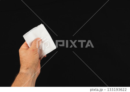 Hand holding a white napkin against a black background 133193622