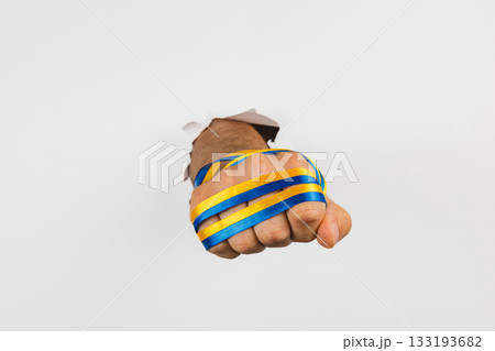 Fist breaking through wall with blue and yellow stripes for support 133193682
