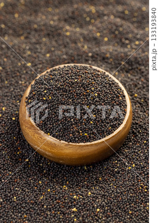 a large number of black rapeseed seeds are used to produce rapeseed oil, black rapeseed is used to produce food products, round wooden bowl filled with round rapeseed 133193840