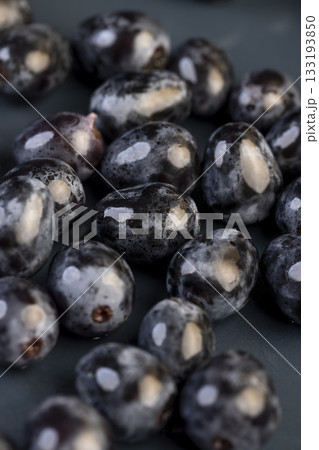 a beautiful ripe grape, torn from a branch, lying on a bowl, covered with drops of water, wet fruits of pure blue grapes on a blue bowl during cooking 133193850