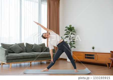 Young Asian woman stretching yoga workout on exercise mat in living room at home Young Asian woman stretching yoga workout on exercise mat in living room at home 133193915