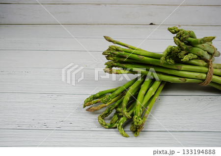 Bunch of fresh green asparagus stems on wooden background Bunch of fresh green asparagus stems on wooden background 133194888