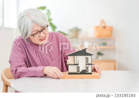 住宅模型を持つグレイヘアーのシニア女性（家づくり,注文住宅,マイホーム) 133195193