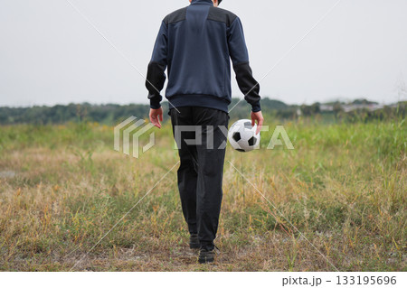 サッカーボールを蹴る男性の後ろ姿 133195696