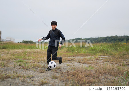 笑顔でサッカーボールを追いかける男性 133195702