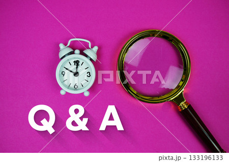 Alarm clock and a magnifying glass on a bright pink background, with text "Q & A" 133196133