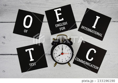TOEIC Test of English for International Communication with alarm clock on wooden background 133196190