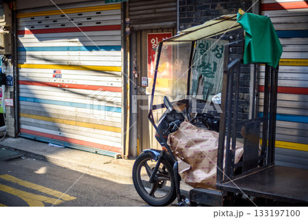A parked motorized rickshaw on a narrow street with closed shops in Myeongdong shopping district in Seoul, South Korea A parked motorized rickshaw on a narrow street with closed shops in Myeongdong shopping district in Seoul, South Korea 133197100