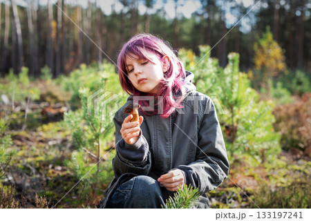 Girl with pink hair holding mushroom exploring forest 133197241