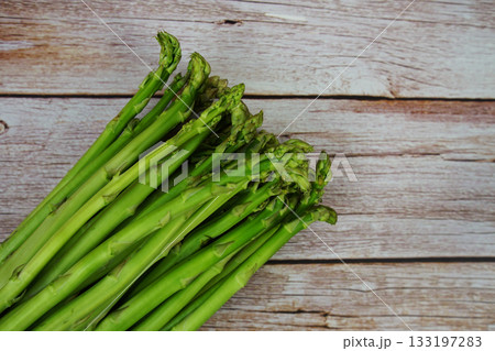 Bunch of fresh green asparagus stems on wooden background 133197283
