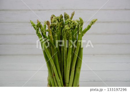 Bunch of fresh green asparagus stems on wooden background Bunch of fresh green asparagus stems on wooden background 133197296