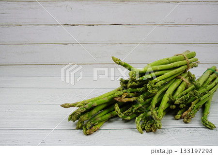 Bunch of fresh green asparagus stems on wooden background 133197298