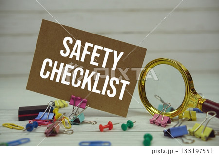 Safety Checklist text on paper card with magnifying glass and stationary on wooden background Safety Checklist text on paper card with magnifying glass and stationary on wooden background 133197551