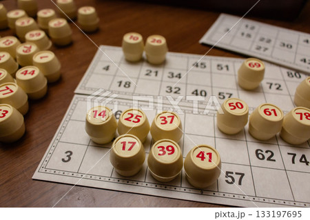 Playing lotto game. Cubes with figure on bingo card background. Nostalgia lifestyle. Table games. Retro games. Barrel with number and paper cards for bingo game. Holiday leisure. Luck concept. 133197695