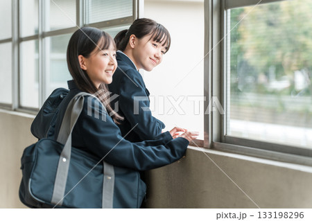 学校の廊下で会話する制服姿の中学生の女子生徒 133198296
