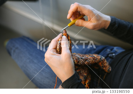 Young caucasian female knitting with crochet hook in hands Young caucasian female knitting with crochet hook in hands 133198550