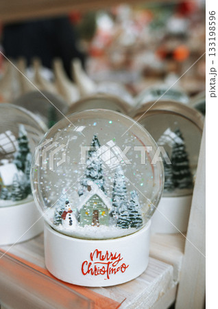 Festive holiday snow globe with cottage and snowman scene 133198596