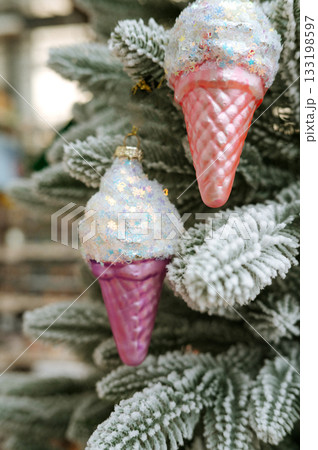 Festive ice cream cone ornaments on snowy christmas tree 133198597