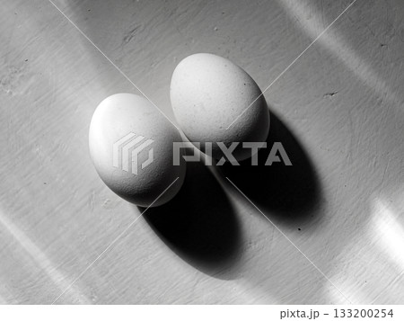 Two white eggs on a white painted board background 133200254