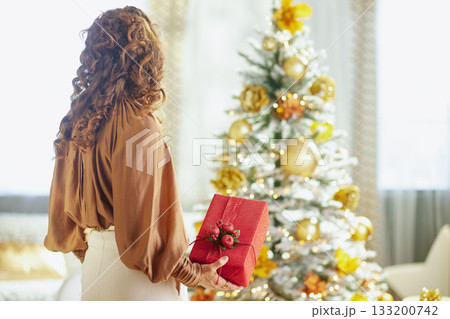 Elegant Woman with Festive Red Gift, Back View 133200742