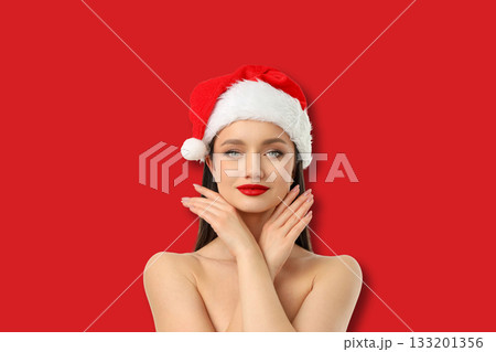 Woman with long dark hair and red lips poses in a Christmas hat 133201356