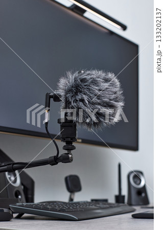 black professional boom microphone stand used for recording voice in online podcast in home studio. fluffy microphone and computer on the table black professional boom microphone stand used for recording voice in online podcast in home studio. fluffy microphone and computer on the table 133202137