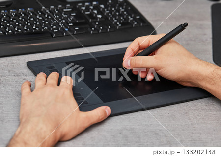 male hands drawing and retouching image on pc computer, using graphic digital tablet and stylus pen at office desk. 133202138