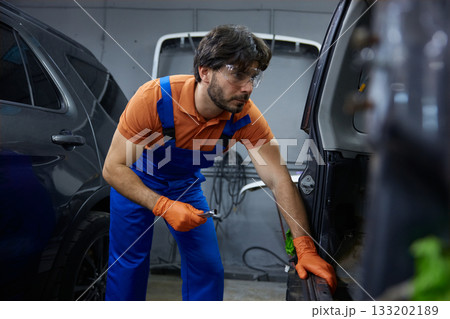 Mechanic repairing car door in garage workshop Mechanic repairing car door in garage workshop 133202189